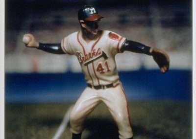 A close-up of a detailed figurine of a baseball player mid-pitch, wearing a white and red uniform labeled "braves" with the number 41, on a blurred stadium background.