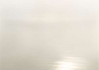 A tranquil, minimalist image featuring a serene water surface under a soft, foggy sky with gentle light reflections. the colors are muted, blending pale yellows and whites.