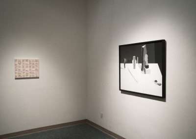 Art gallery corner with two artworks on display: on the left, a framed piece with red and white patterned squares; on the right, a minimalist black and white cityscape painting.