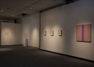 Art gallery interior with dim lighting showcasing various framed artworks on white walls, enhancing a calm and reflective ambiance.