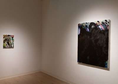 Two abstract paintings displayed on a gallery wall. The smaller one on the left features vibrant colors and the larger one on the right is dominantly black with colored streaks.