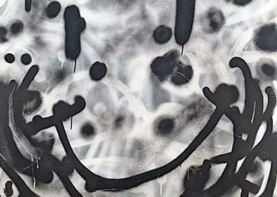 Abstract black and white monoprint featuring smeared patterns, drips, and circular shapes resembling a stylized face with a smile. The artwork has a raw, emotive expression with a focus on texture and contrast.