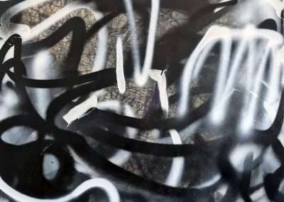 Abstract graffiti art with white and grey spray paint swirls on a textured dark background, creating a chaotic and expressive design.
