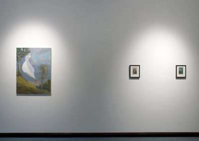 An art gallery wall with three framed paintings under spotlighting; the larger central piece features a surreal outdoor scene, flanked by two smaller *DIY painting* works.