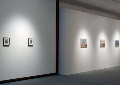 A modern art gallery interior with white walls featuring evenly spaced framed paint by numbers pieces illuminated by spotlights.