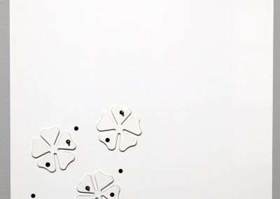 Minimalist artwork on a white canvas featuring a cluster of abstract black and white shapes resembling stylized flowers or splatters, arranged towards the bottom left corner.