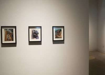 Four framed paintings displayed on a well-lit gallery wall, each featuring unique, abstract art styles.
