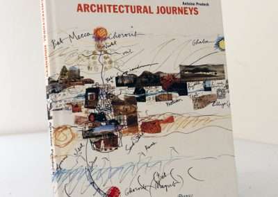 A book titled "Architectural Journeys" by Antoine Predock, displayed upright against a white background, featuring a cover with colorful, abstract illustrations and signatures.