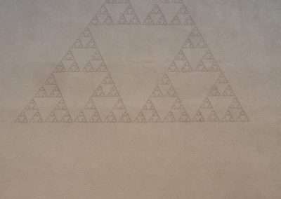 A large Sierpinski triangle mural painted on a concrete wall, featuring a fractal geometric pattern forming smaller triangles within a larger triangle.