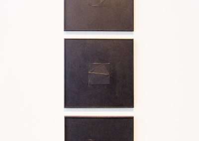 Three vertically aligned black canvases on a white wall, each featuring a different geometric wire sculpture in low relief.