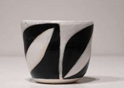 A ceramic cup, one of my favorite things, with a bold black and white abstract design, positioned against a light grey background.