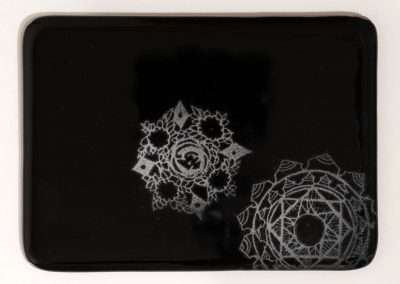 A black rectangular surface displaying two intricate white crochet doilies, favorite things with detailed geometric patterns, one slightly overlapping the other.