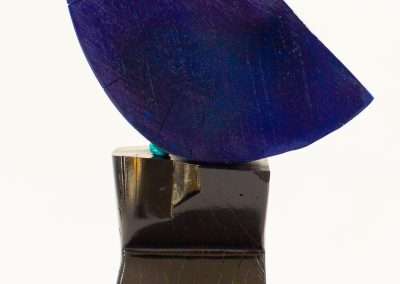 A contemporary sculpture featuring a metallic black base supporting a large, textured blue leaf-like shape, showcasing one of our favorite things in modern art design.