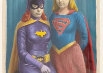 Two children dressed as superheroes, with one in a Batman costume and the other in a Supergirl costume, standing against a dark blue background.