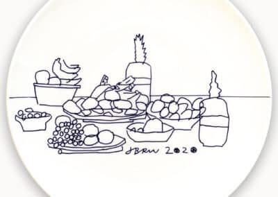 A line drawing on a white plate featuring various fruits such as bananas and grapes, two bottles, and a bowl, artistically signed "jbrow 2020.